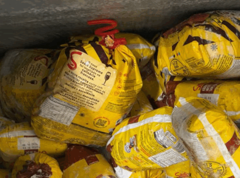 Diversos frangos congelados da marca Sadia embalados em sacos amarelos, empilhados dentro de um freezer industrial.