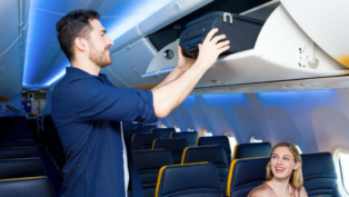 Homem guardando mala de mão no bagageiro do avião