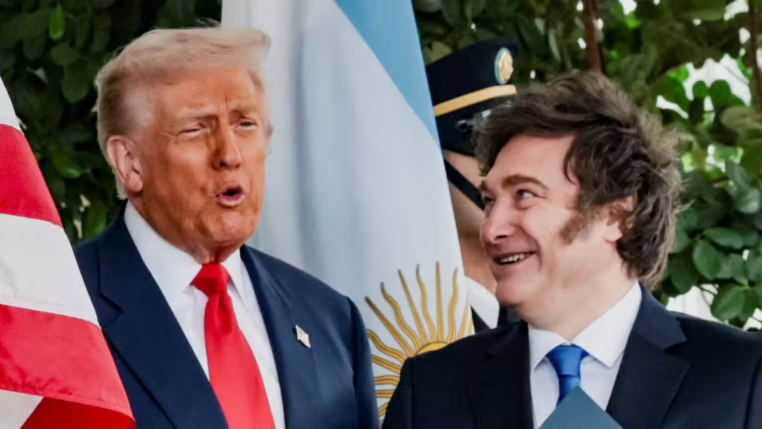 Trump e Milei lado a lado, conversando, com as bandeiras da Argentina e Estados Unidos ao fundo