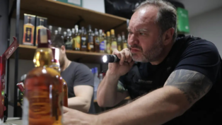 Policial aponta lanterna para uma bebida alcoólica