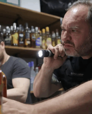 Policial aponta lanterna para uma bebida alcoólica