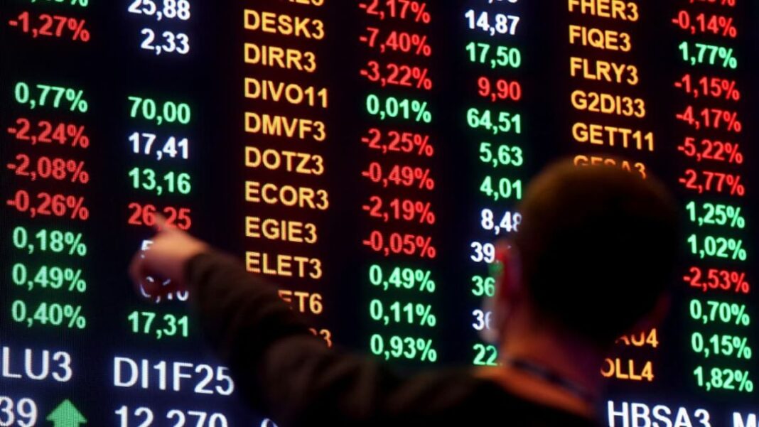 Homem aponta para números em painel da bolsa de valores