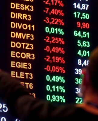 Homem aponta para números em painel da bolsa de valores