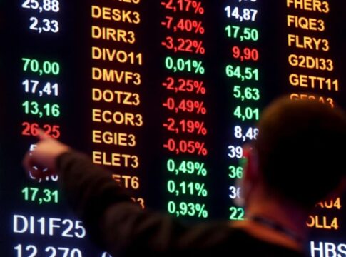 Homem aponta para números em painel da bolsa de valores