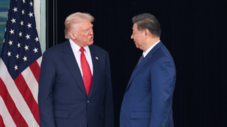 Donald Trump e Xi Jinping se olham ao lado da bandeira dos EUA