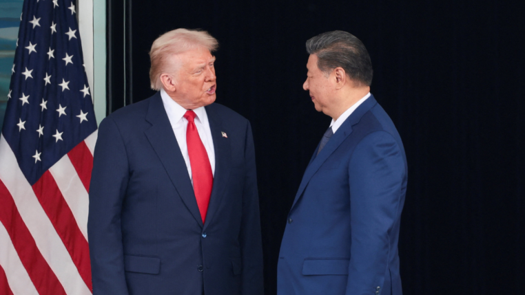 Donald Trump e Xi Jinping se olham ao lado da bandeira dos EUA