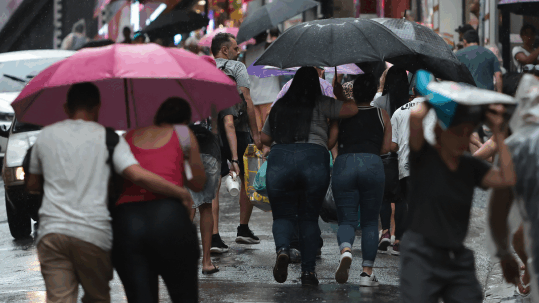 Pessoas em São Paulo andando sob um guarda-chuva em dia chuvoso na capital