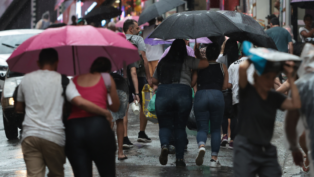 Pessoas em São Paulo andando sob um guarda-chuva em dia chuvoso na capital
