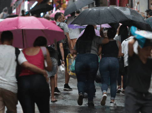 Pessoas em São Paulo andando sob um guarda-chuva em dia chuvoso na capital