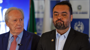 Plano aberto mostra o governador do Rio de Janeiro, Cláudio Castro, e logo atrás, olhando pra ele, o ministro da Justiça e Segurança Pública, Ricardo Lewandowski