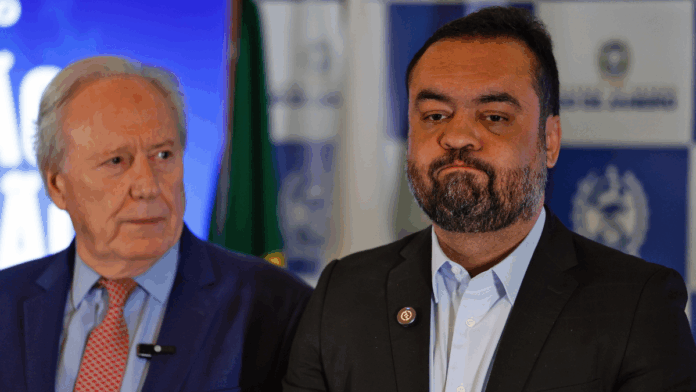 Plano aberto mostra o governador do Rio de Janeiro, Cláudio Castro, e logo atrás, olhando pra ele, o ministro da Justiça e Segurança Pública, Ricardo Lewandowski