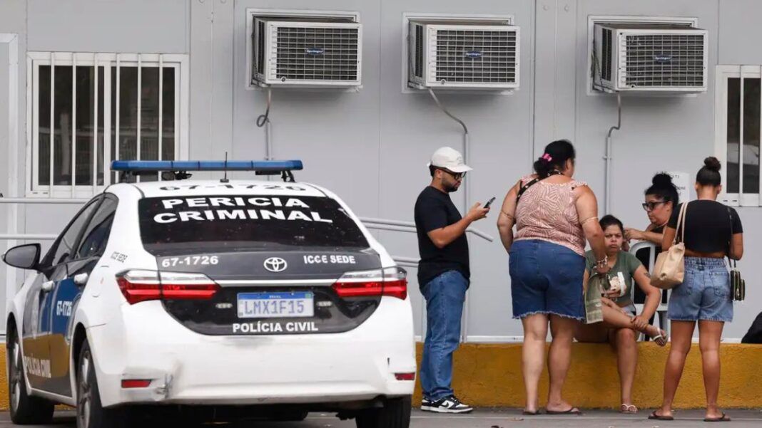 Pessoas estão ao lado de um carro da Perícia Criminal à espera de informações no IML