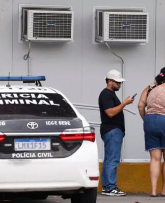 Pessoas estão ao lado de um carro da Perícia Criminal à espera de informações no IML