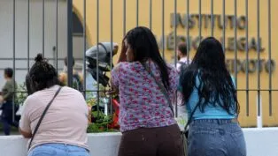 Mulheres aguardam diante do portão do Instituto Médico Legal