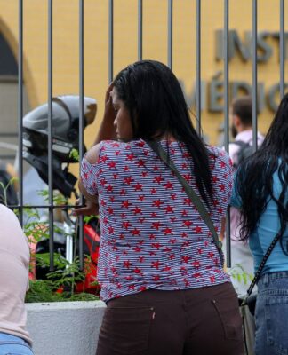 Mulheres aguardam diante do portão do Instituto Médico Legal