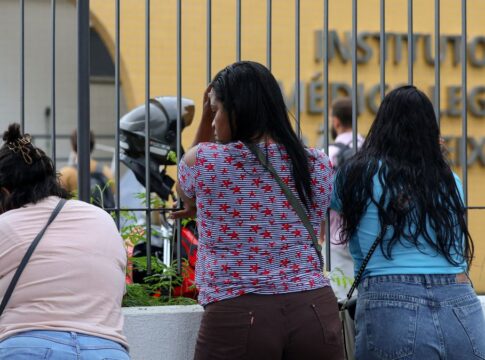Mulheres aguardam diante do portão do Instituto Médico Legal