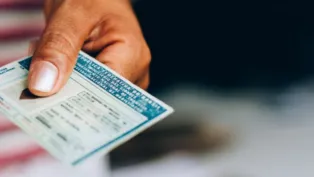 Mão de uma pessoa negra segurando uma CNH