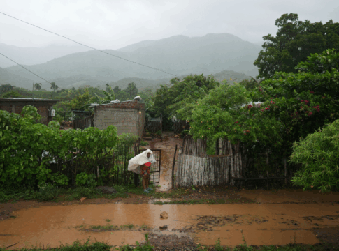 Mulher tenta se proteger do furacão em frente a uma rua alagada