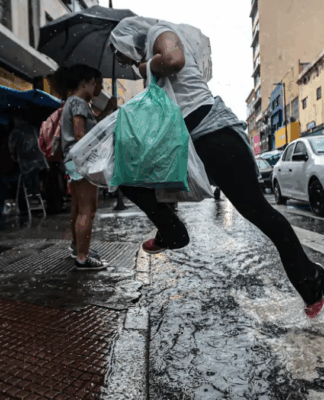 Imagem colorida de homem pulando uma poça d'água ao atravessar a rua