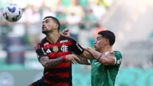 O jogador Emiliano Martínez, do Palmeiras, disputa bola com Arrascaeta do Flamengo