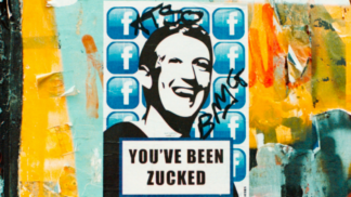 Em um parede com grafites, há um poster com uma ilustração do rosto de Mark Zuckenberg, CEO da Meta, com a seguinte frase em inglês: "Você foi Zuckeado"