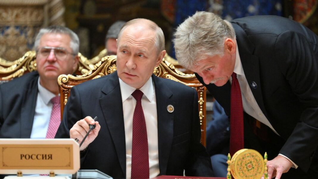 Porta-voz russo, Dmitry Peskov, fala ao ouvido do presidente Vladimir Putin