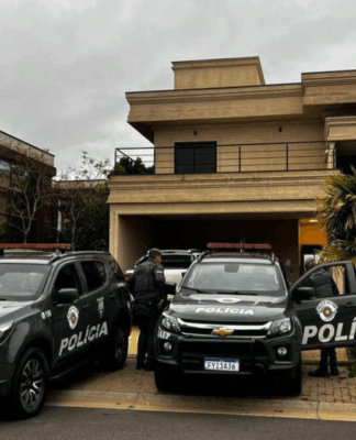 Dois carros da Polícia Militar em frente a uma casa