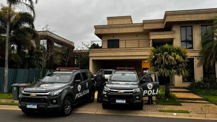 Dois carros da Polícia Militar em frente a uma casa