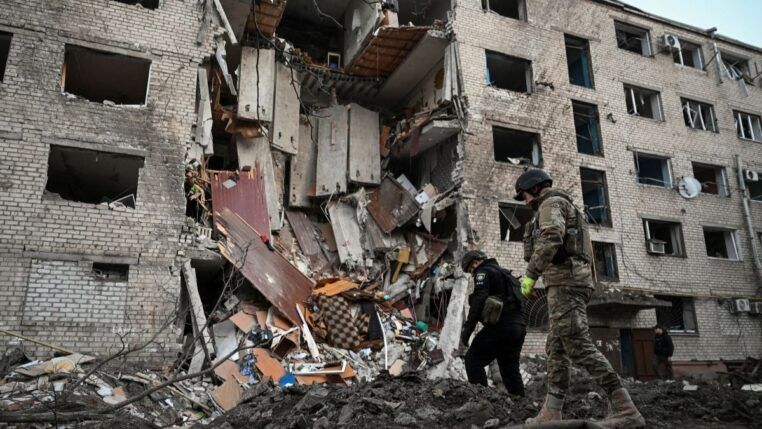 Soldados ucranianos inspecionam destroços de um prédio vitimado pelo bombardeio russo