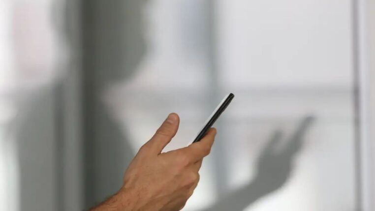 Imagem colorida de pessoa segurando o celular