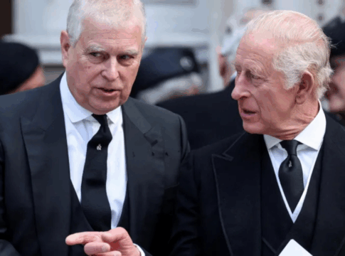 Dois homens mais velhos, vestidos com ternos pretos e gravatas escuras, conversam de forma séria durante um evento formal. Um deles gesticula com a mão enquanto o outro o escuta atentamente. Ao fundo, há outras pessoas também trajadas de preto, sugerindo uma ocasião solene, como uma cerimônia ou funeral.