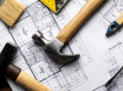 Ferramentas de construção sobre plantas arquitetônicas. Imagem ilustrativa de reformas e projetos habitacionais.