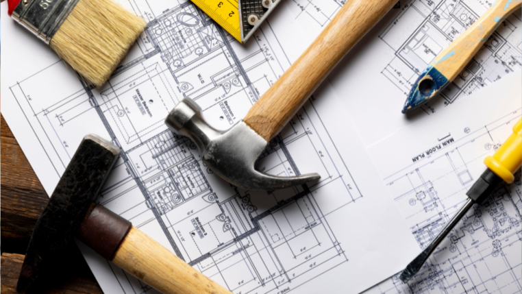 Ferramentas de construção sobre plantas arquitetônicas. Imagem ilustrativa de reformas e projetos habitacionais.