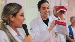 Dentistas do SUS fazendo uma apresentação com uma boca de brinquedo gigante