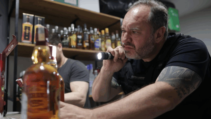 homem analisa garrafa de bebida adulterada