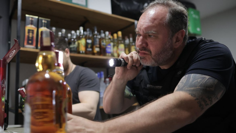 homem analisa garrafa de bebida adulterada