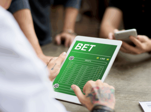 Close na mão de uma pessoa navegando em uma página de bet, em um tablete