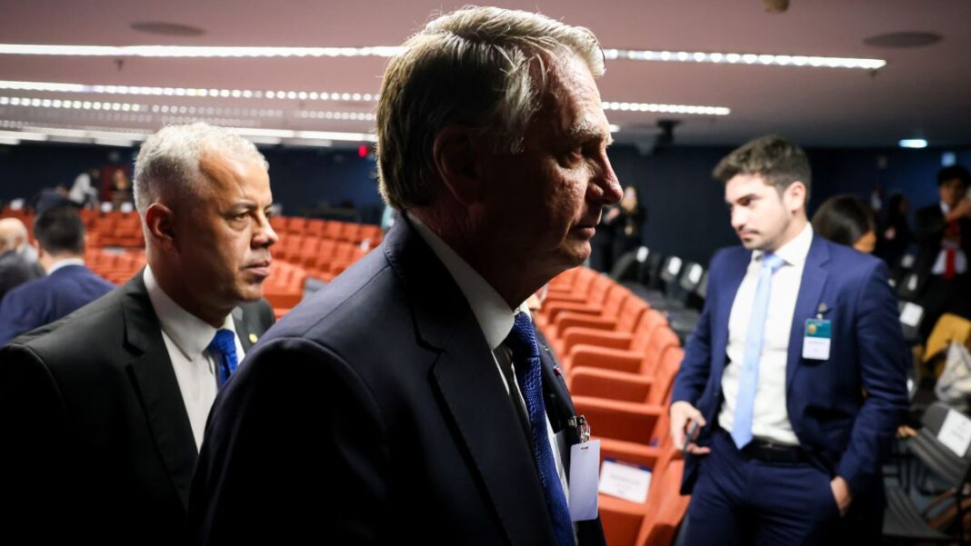 Imagem mostra o ex-presidente Jair Bolsonaro em audiência do julgamento da tentativa de golpe. Ele aparece no primeiro plano, com uma sombra que deixa apenas a silhueta do rosto dele. Atrás aparecem cadeiras da audiência.