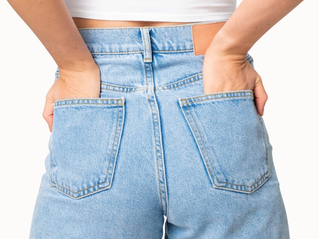 Mulher de costas vestindo calça jeans com as mãos no bolso