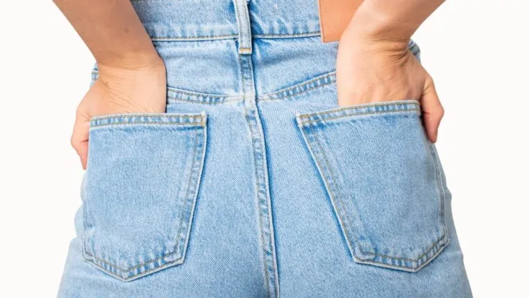 Mulher de costas vestindo calça jeans com as mãos no bolso