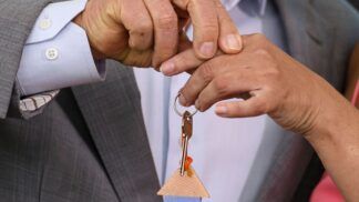 Pessoas segurando uma chave com logotipo da Caixa Econômica Federal