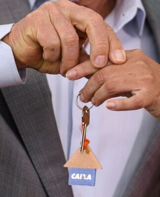 Pessoas segurando uma chave com logotipo da Caixa Econômica Federal