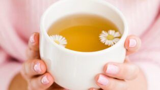 Mulher segurando xícara com chá de camomila