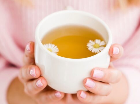 Mulher segurando xícara com chá de camomila