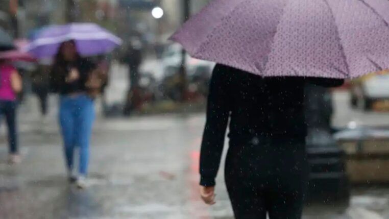 Pessoas andando na rua com guarda-chuva durante temporal