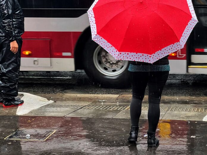 Pessoas andando na Avenida Paulista com guarda-chuva durante temporal