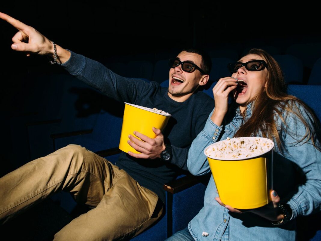 Homem e mulher comendo pipoca no cinema