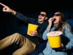 Homem e mulher comendo pipoca no cinema