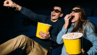 Homem e mulher comendo pipoca no cinema