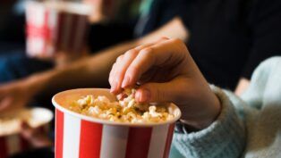 Pessoa comendo pipoca no cinema